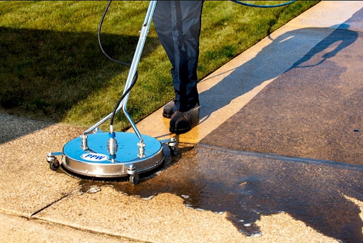 Rotary surface cleaner rinsing a concrete driveway